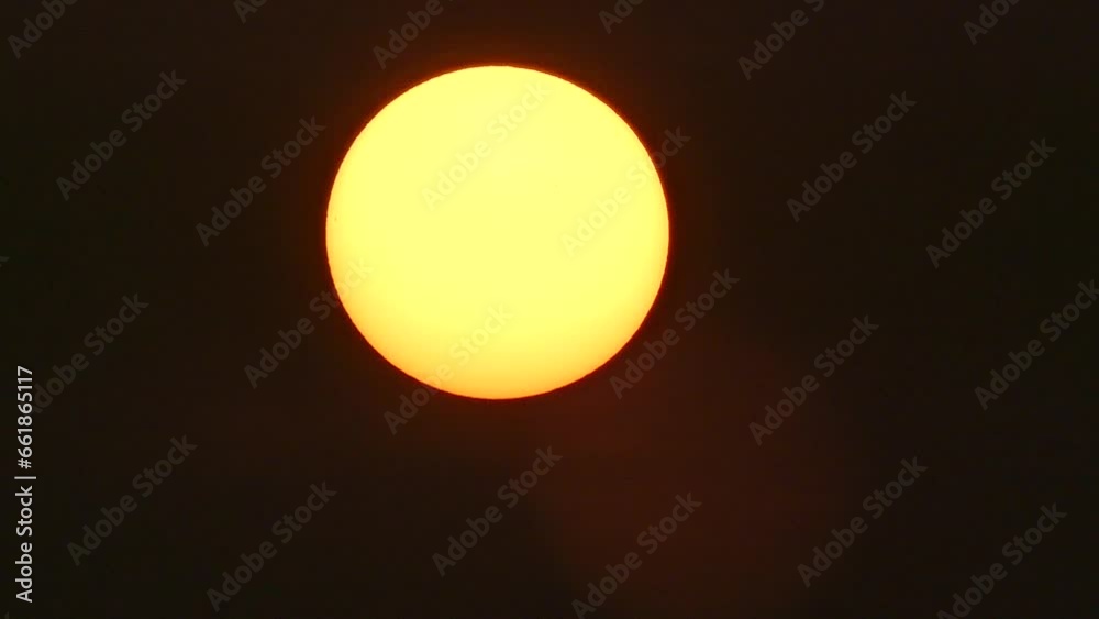 Dark sky and yellow solar disk with red edge during sunrise and visible sun spots in month of March in 2016 - real time. Topics: sun energy, sunbursts, science, weather, atmosphere, space, dawn