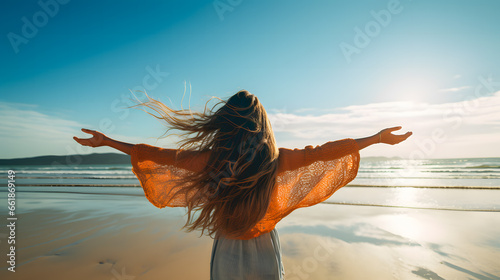 Une femme de dos les bras tendu en train de savourer un moment de bonheur au bord de mer.  photo