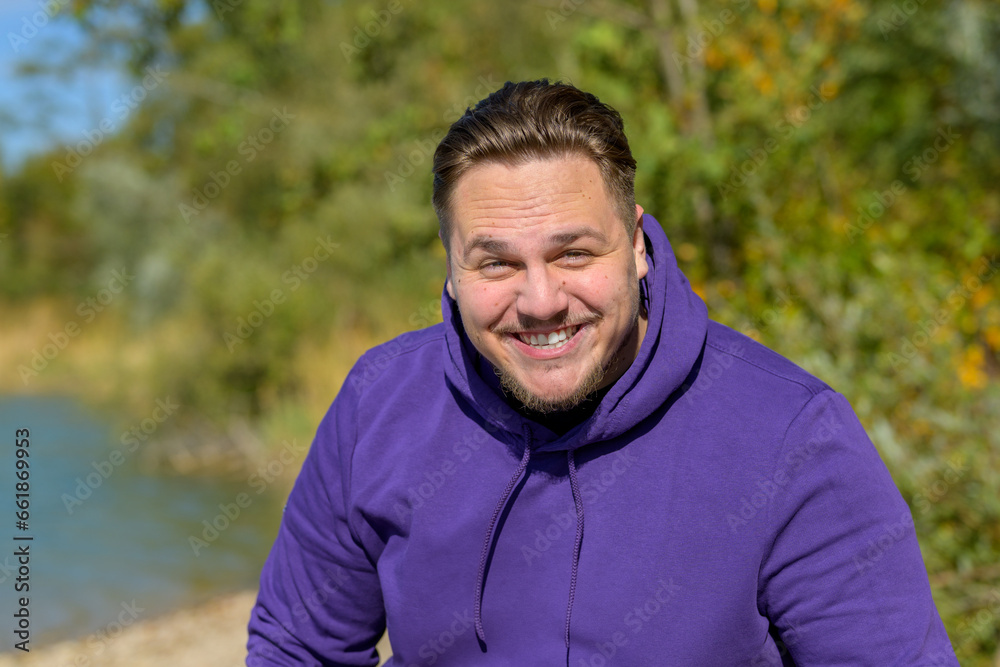 Young attractive man wearing a purple hoodie laughing funny Young attractive man wearing a purple hoodie laughing funny