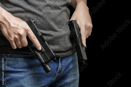 Hided handgun under the denim belt. a man in jeans and a t-shirt holds a gun in his hand from the back