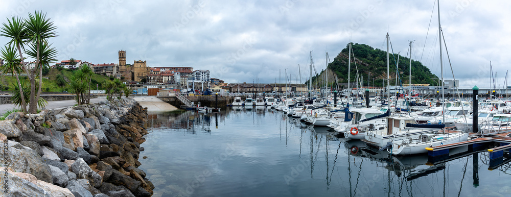 Obraz premium Panoramic view of Getaria fishing port with the old town on one side and Mount San Anton on the other on a cloudy day, Gipuzkoa, Basque Country, Spain