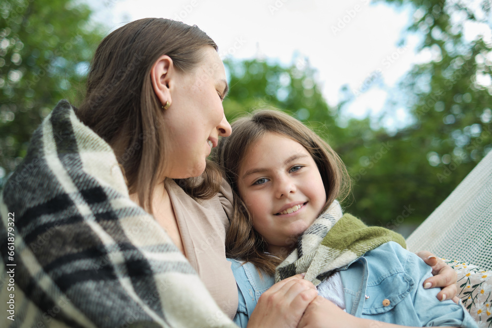 The simple act of hugging brings unparalleled joy to a mother and daughter, swinging in a garden hammock. The simple act of hugging brings unparalleled joy to a mother and daughter, swinging in a garden hammock.