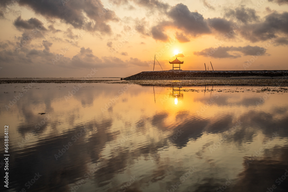 Beautiful sunrise on Sanur beach. Temple in the calm sea. Small waves in the morning. Sandy beach on the dream island of Bali. Sunset in a landscape shot, looking into the horizon Beautiful sunrise on Sanur beach. Temple in the calm sea. Small waves in the morning. Sandy beach on the dream island of Bali. Sunset in a landscape shot, looking into the horizon