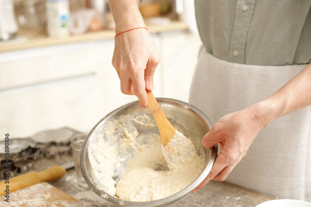 Fototapeta premium Young man kneading dough on wooden table. Males hands making bread on the kitchen. Baking concept.
