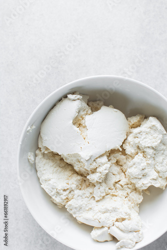 Strained Greek yogurt in a white ceramic bowl, process of making Greek yogurt, strained thick yogurt in white mixing bowl