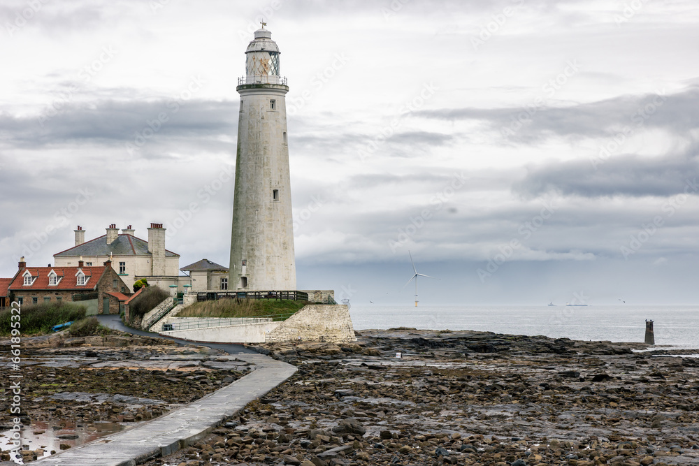 Obraz premium St. Mary's Lighthouse with a large offshore windmill, turbine for alternative green, renewable energy, electricity, just of the English coast. Whitley Bay, Newcastle, UK