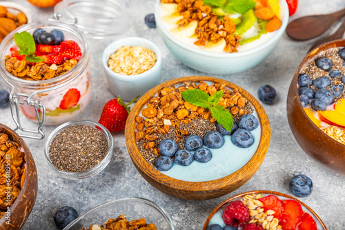 Bowl of granola with yogurt and fresh berries on a texture table. Yogurt berries, acai bowl, spirulina bowl. Healthy food, balanced breakfast. Strawberries, blueberries, kiwi, peach, almonds and chia.