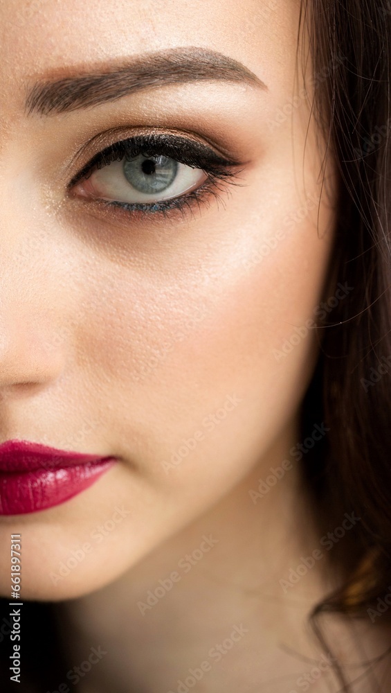 Close-up of the eye makeup half of the face of a blue-eyed girl with bright lips Close-up of the eye makeup half of the face of a blue-eyed girl with bright lips
