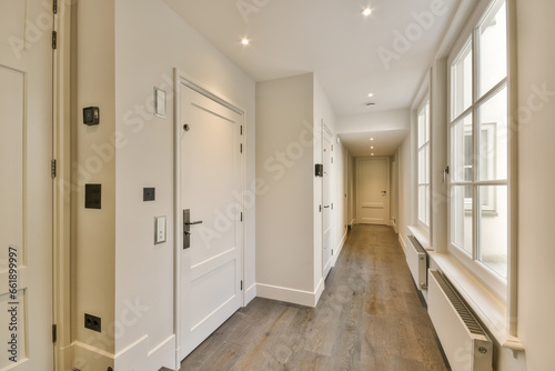 a long hallway with wood flooring and white trim on the walls, leading to an open door that leads to another room