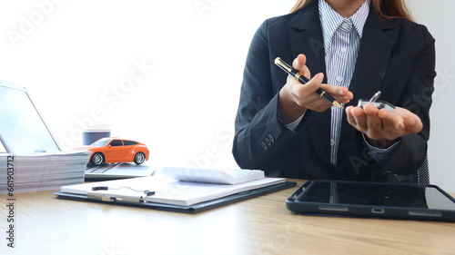 Car salesman holds keys at car dealership in office