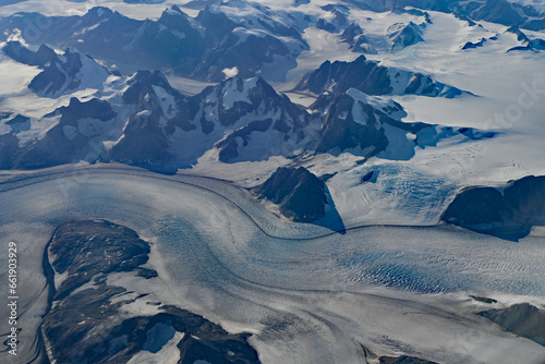 Aerial view of mountains, snowfields and glacier in southern Greenland on clear sunny autumn day.