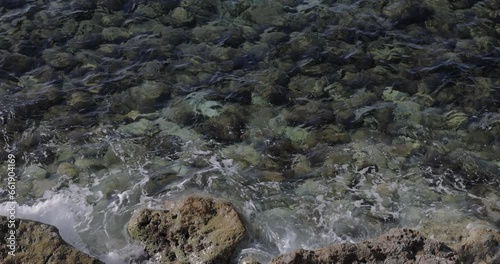 top view of a blue water waves above stones on the bottom
