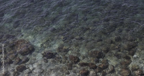 top view of a blue water waves above stones on the bottom