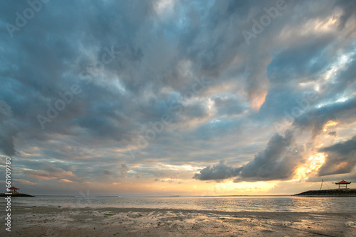 Beautiful sunrise on Sanur beach. Temple in the calm sea. Small waves in the morning. Sandy beach on the dream island of Bali. Sunset in a landscape shot, looking into the horizon © Jan