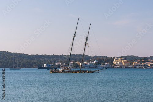 Porto Heli, Greece - 16 February 2023 - Old half sunken sailingboat in the harbour