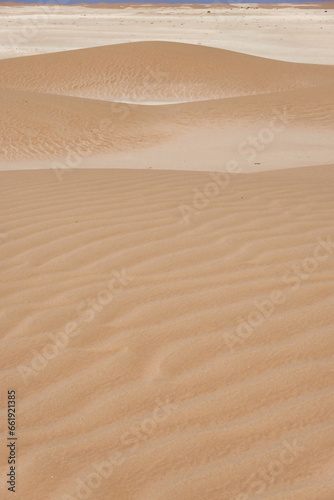 Panorama of small dunes with red sand and vertical streaks on the limestone horizon.