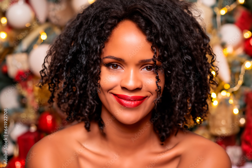 Fototapeta premium Christmas portrait of a black woman with a beautiful smile and medium length hair against the background of Christmas baubles and lights