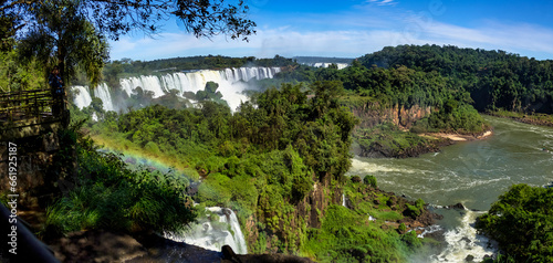 Panorama of Iguazu  Iguacu  waterfall with rainbow cascade waterfalls landscape in Argentina. Powerful natural falls in greenery rainforest  summer sun day. World nature concept. Copy ad text space