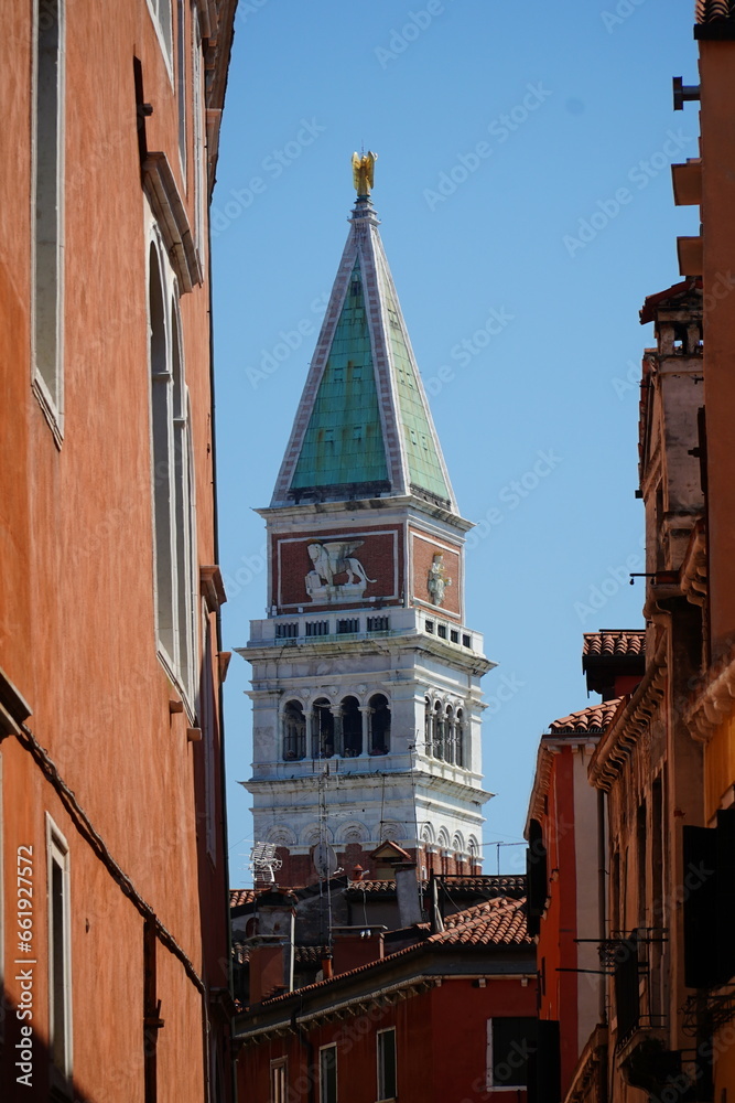 The top of the Campanile bell tower at Saint Marks Square (Piazza San Marco) behind the narrow streets of the historic lagoon city Venice, Italy.