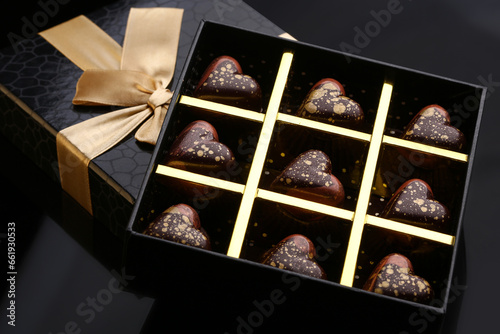 Heart shaped painted luxury handmade bonbons in a gift box on a black background. Chocolates for Valentine's Day.