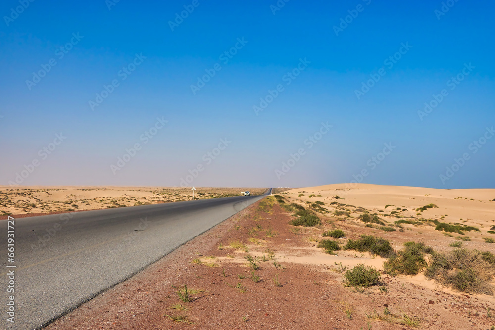 Oman paved road with golden desert on the side.