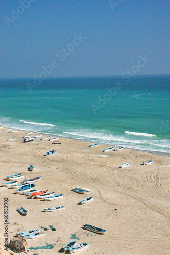 Vertical photo from above fishermen's boats on the beach on the horizon blue green sea. Oman. © Ombres
