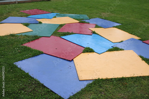 Various square coloured mats spread out on the grass outdoors yellow mat, blue, red, cyan, green