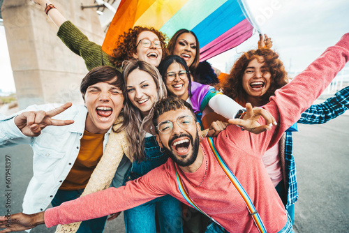 Diverse group of cheerful young people celebrating gay pride day - Lgbt community concept with guys and girls hugging together outdoors photo
