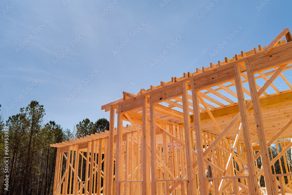 Construction work in progress on an unfinished house with wooden framing beams