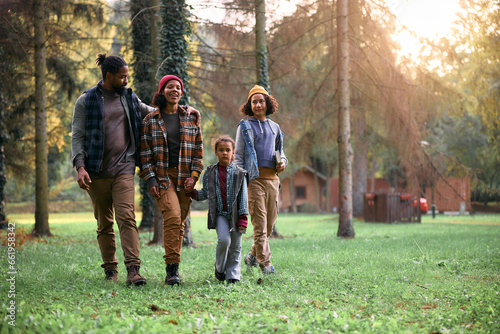 Black parents with kids enjoying in autumn walk in forest.