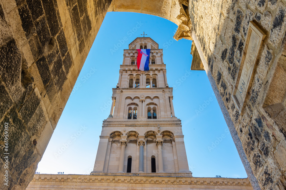 Cathedral of Saint Domnius' bell tower with Croatian flag waving in the wind in  Diocletian palace, Split, Croatia. Diocletian palace UNESCO world heritage site in Split, Croatia - obrazy, fototapety, plakaty 