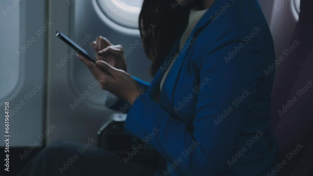 Traveling and technology. Flying at first class. Pretty young businees woman using smartphone while sitting in airplane.. Traveling and technology. Flying at first class. Pretty young businees woman using smartphone while sitting in airplane..