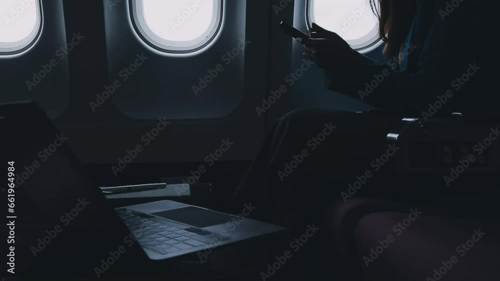 Traveling and technology. Flying at first class. Pretty young businees woman using smartphone while sitting in airplane.. Traveling and technology. Flying at first class. Pretty young businees woman using smartphone while sitting in airplane..