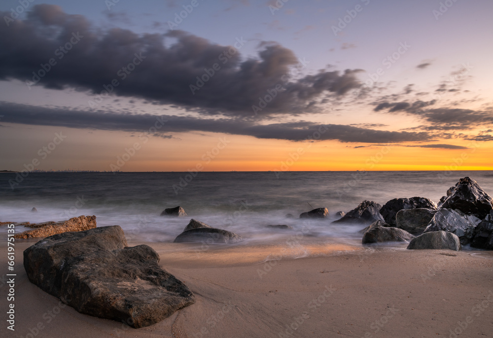Beautiful tranquil dawn scene at Sandy Hook Beach in New Jersey, featuring sand and rocks on the background