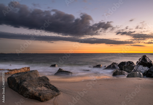 Beautiful tranquil dawn scene at Sandy Hook Beach in New Jersey  featuring sand and rocks on the background
