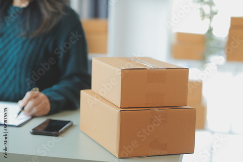 Startup SME small business entrepreneur of freelance Asian woman using a laptop with box Cheerful success Asian woman her hand lifts up online marketing packaging box and delivery SME idea concept