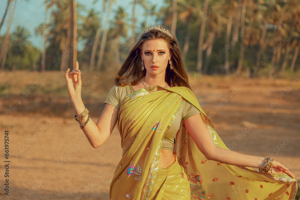 Naklejka premium Young fashion woman demonstrating traditional Indian saree.