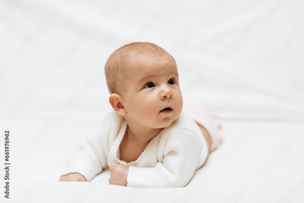 Funny infant girl in knitted clothes is lying on white background. Close up. Copy space. Funny infant girl in knitted clothes is lying on white background. Close up. Copy space.