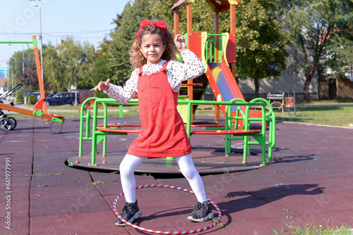 Little girl is playing on the children's playground with hulahop photo