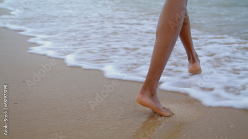 Woman feet walking ocean waves closeup. Unknown playful girl enjoying beach