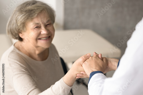 Close up smiling old woman hold doctors hand  get optimistic news after therapy. Therapist supports  encourages old patient  give hope  congratulate with end of treatment. Geriatrics  medical services