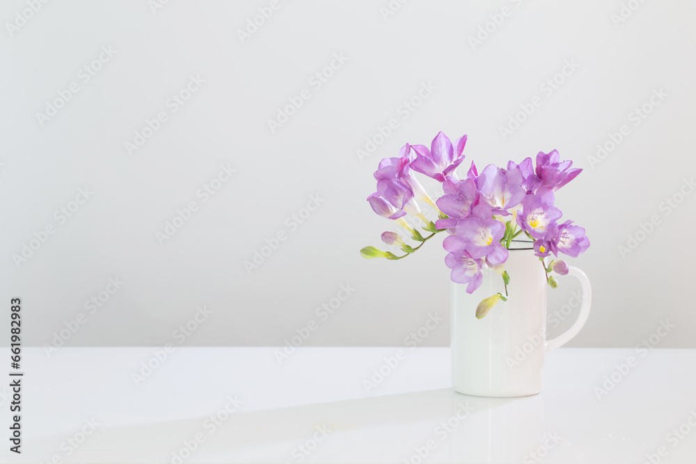 Fototapeta premium purple freesia in glass vase on white background