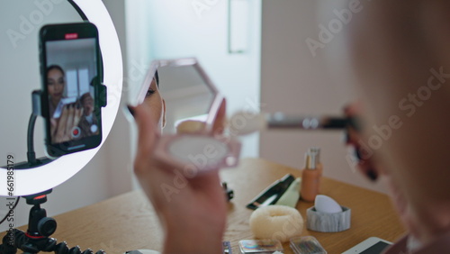 Woman visagiste applying cosmetics at mirror close up. Blogger recording visage