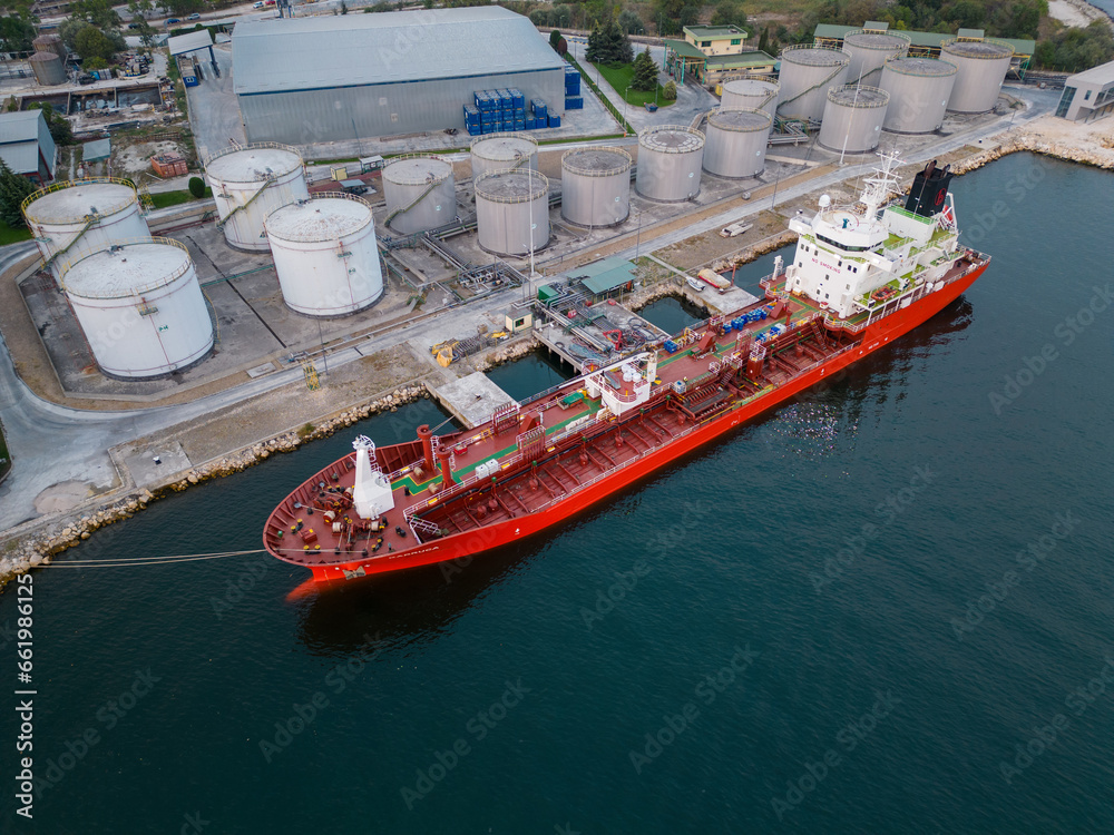 Φωτογραφία Tanker ship refueling at an oil terminal with storage silo's in the port, aerial