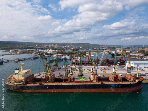 aerial view of a bustling seaport, where a massive cargo ship, a bulk carrier, is being loaded with wheat grains © sandsun