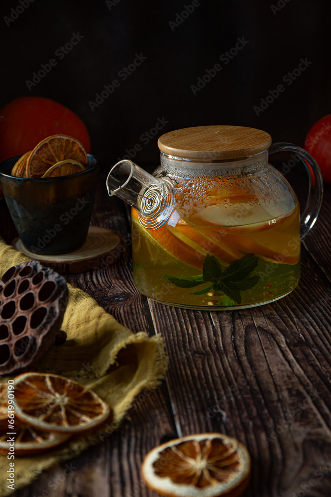 Fruit tea with oranges and mint in glass kettle on wooden table Fruit tea with oranges and mint in glass kettle on wooden table