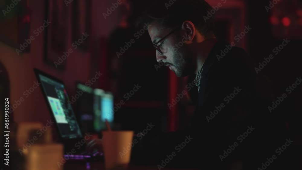 Side view of man working at laptop in home office. Freelance businessman or study online. Make order. Edit text or photoshop images in program. Glowing keyboard in dark. Mock up screen and monitor. Side view of man working at laptop in home office. Freelance businessman or study online. Make order. Edit text or photoshop images in program. Glowing keyboard in dark. Mock up screen and monitor.