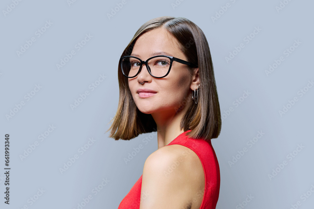 Smiling young woman wearing fashionable glasses, on gray background Smiling young woman wearing fashionable glasses, on gray background