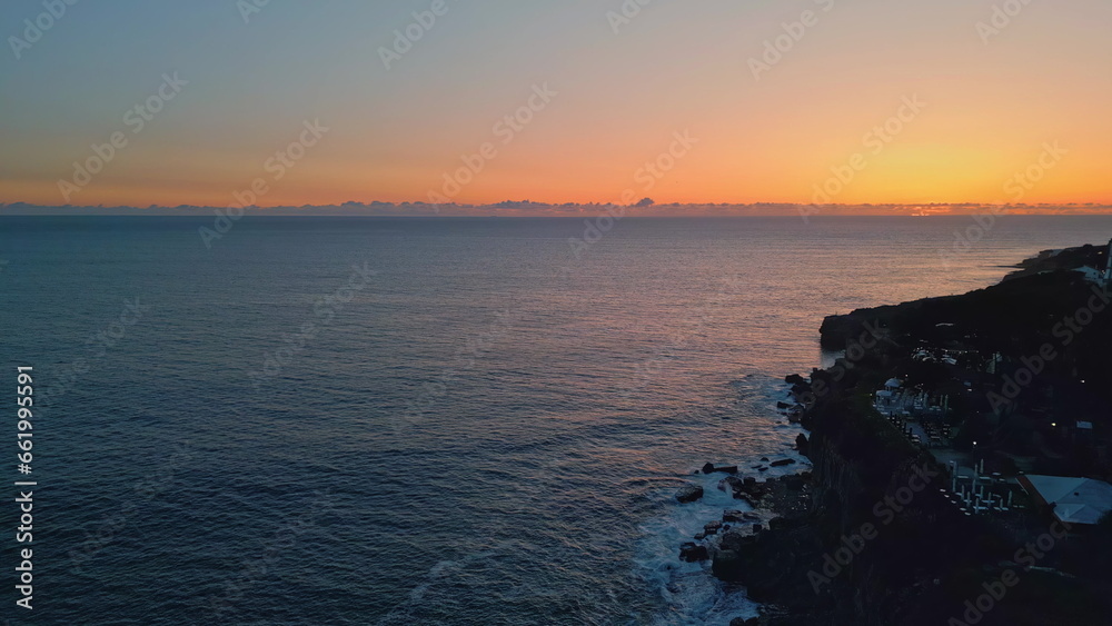 Evening sky marine horizon drone view. Tranquil deep ocean with cliff silhouette