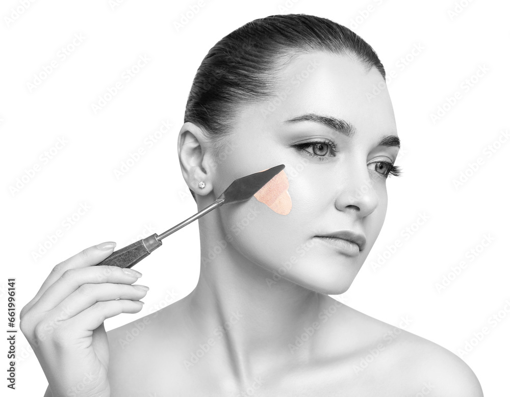 Young woman applying foundation with artistic spatula. Young woman applying foundation with artistic spatula.